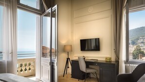 Une chambre d’hôtel avec un lit, un bureau et une chaise, une télévision et une vue sur la mer.