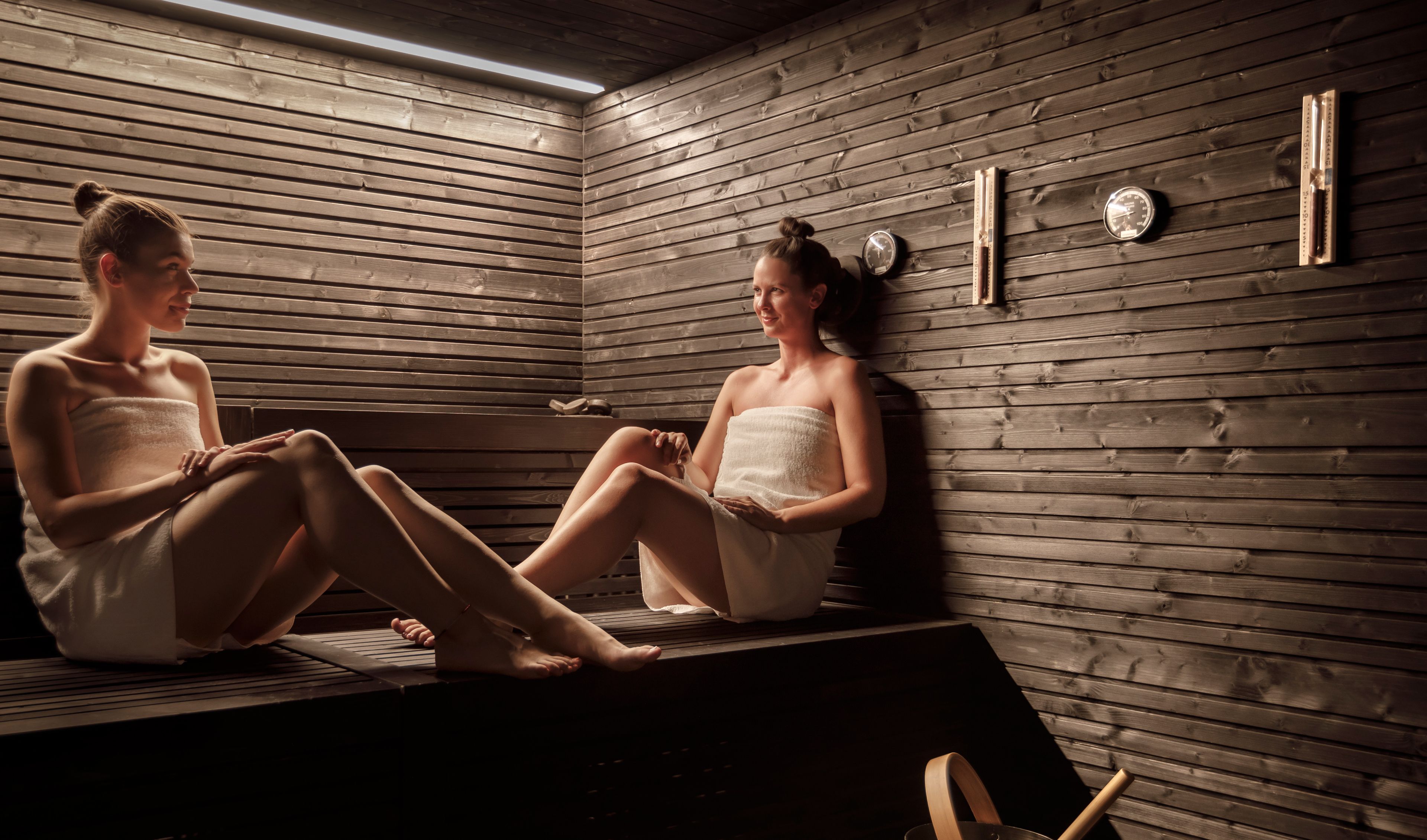 A sauna room with wooden walls, benches, and a visible thermometer.