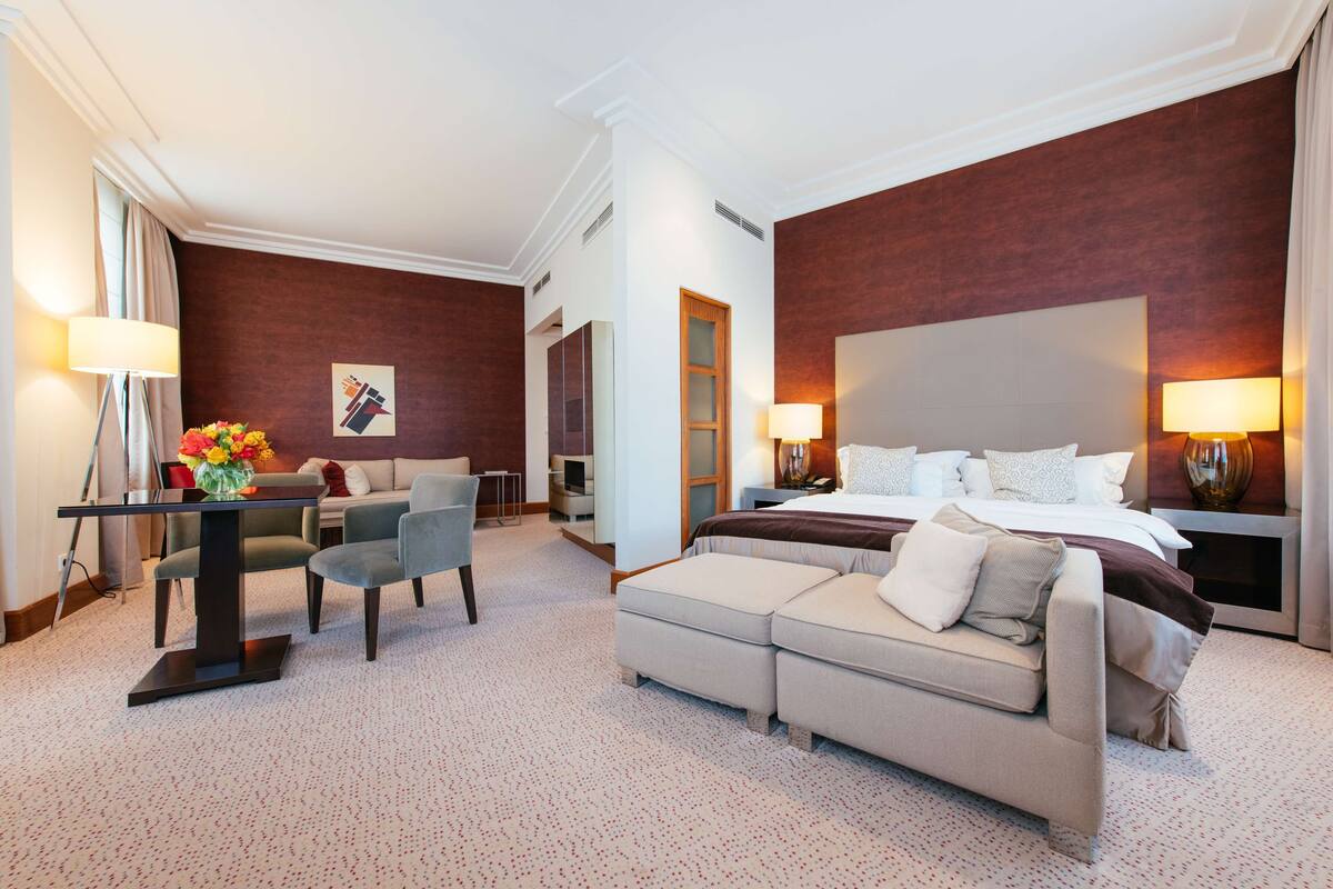 A hotel room with a large bed, a sofa, a desk, and a chair.