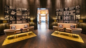 A modern lobby with two sofas facing each other, a chandelier, and a wall with framed pictures.