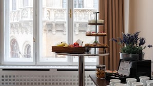 A breakfast buffet with fruits, pastries, and coffee cups by a window with a view of ornate architecture.