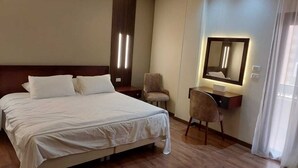 Une chambre d’hôtel avec un grand lit, un bureau avec une chaise, un miroir et une table de chevet.