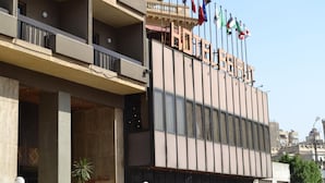 Il s’agit d’un hôtel à la façade moderne, doté de nombreux balcons et d’une enseigne indiquant qu’il s’agit bien d’un hôtel. On peut apercevoir des drapeaux au sommet du bâtiment.