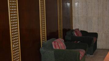 Una habitación con dos sillones verdes y un aparador de madera con un motivo decorativo.