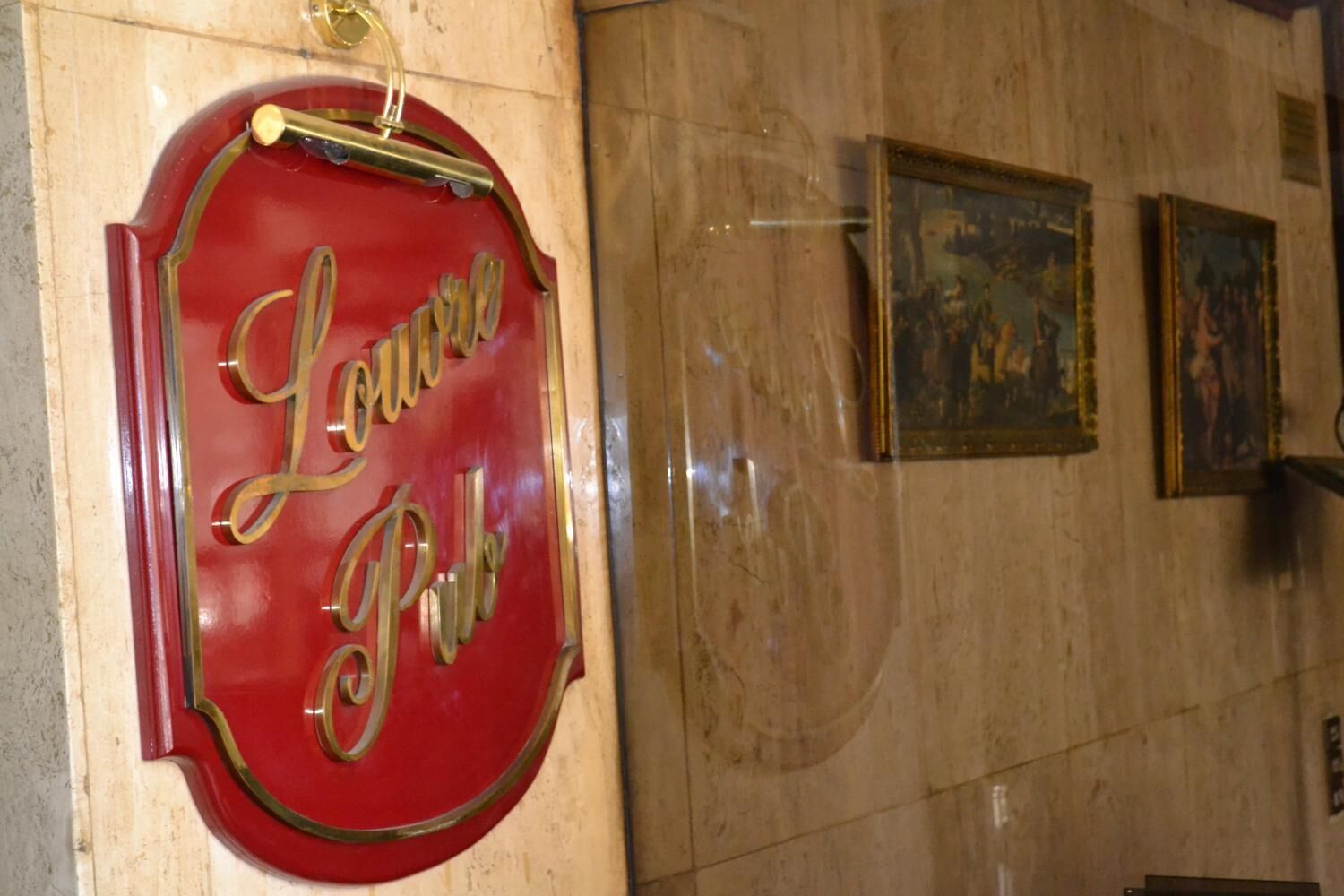 A red sign with gold lettering reading "Louise Pub" mounted on a wall.