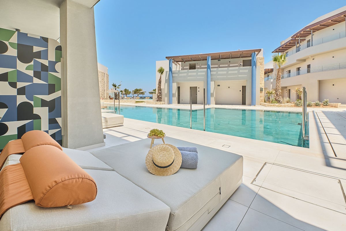 A poolside area with a lounge chair, a hat, and a small table with fruit.