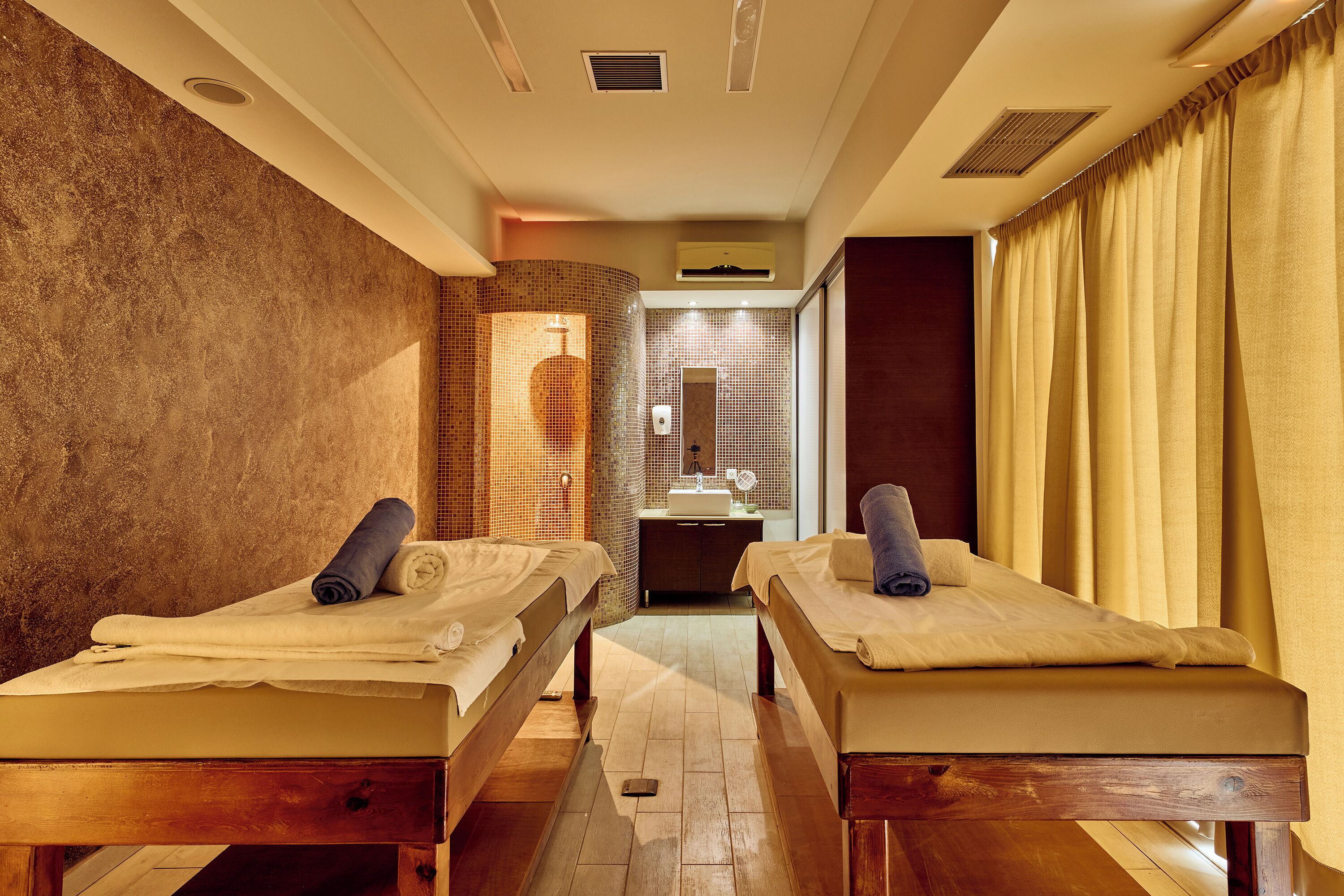 A room with two beds, a sink, and a mirror.