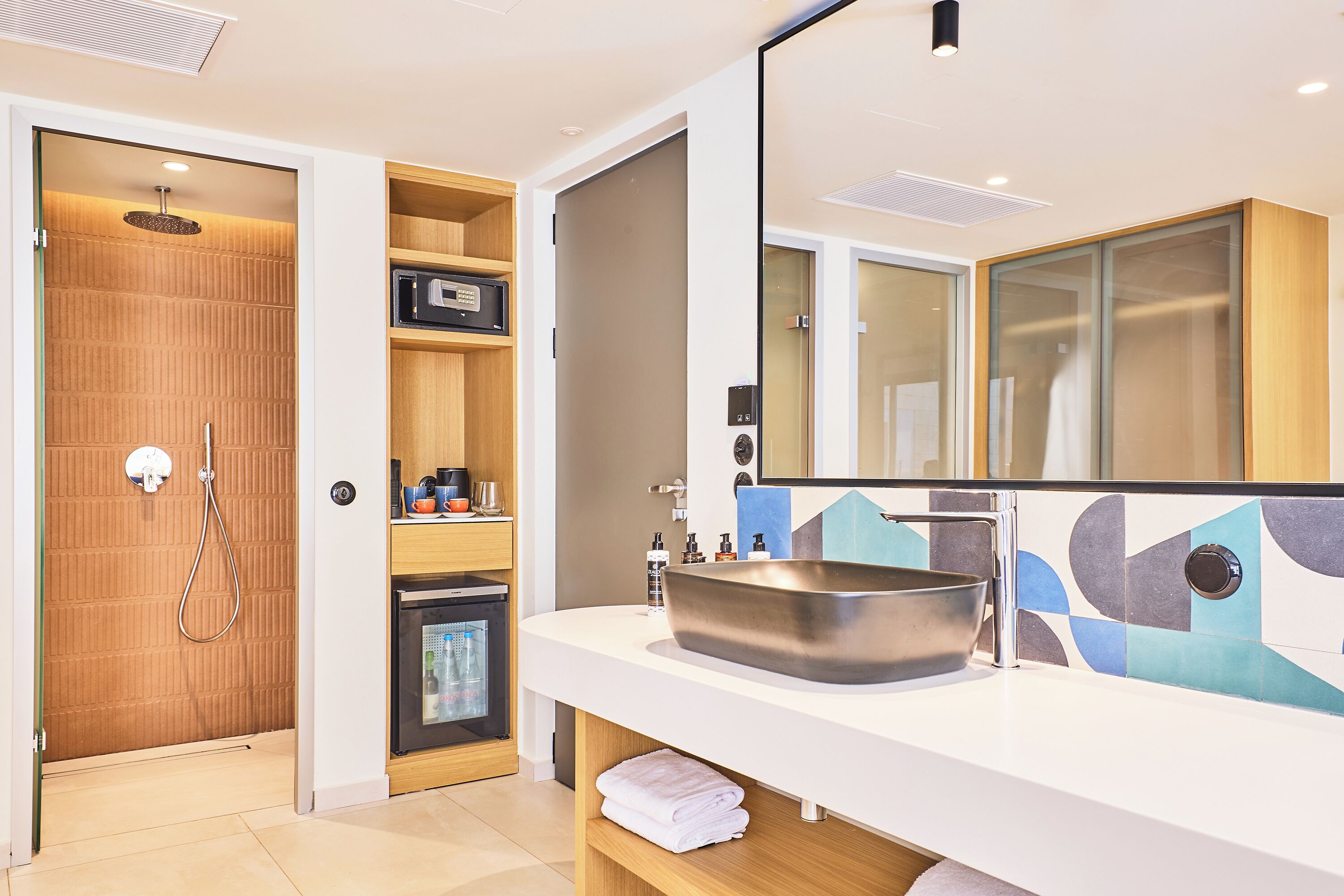 Un baño moderno con un espejo grande, un lavamanos y una ducha.