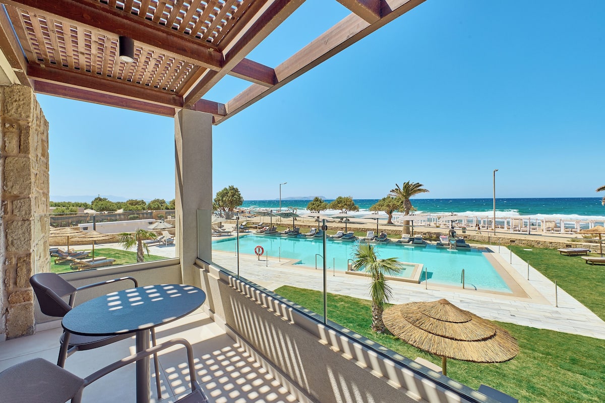 A balcony with a view of a pool and the sea.