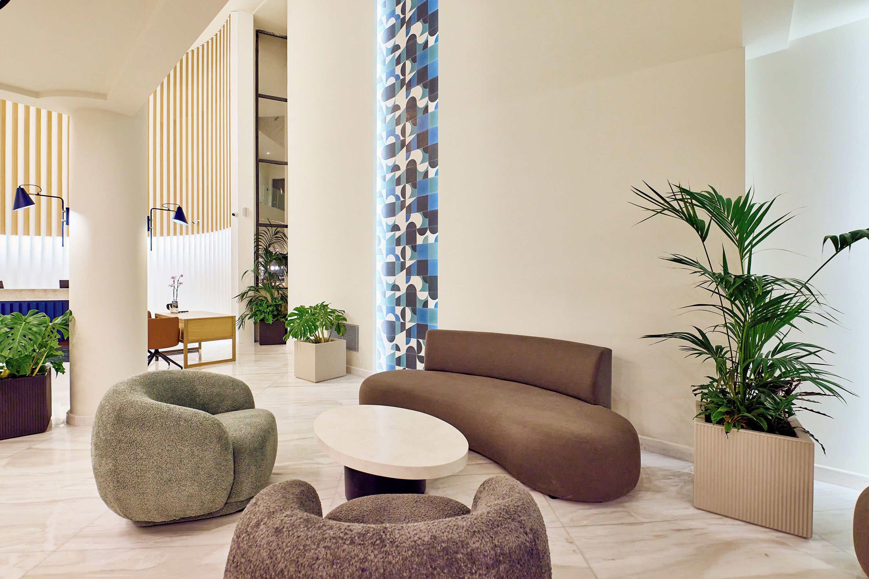 Een moderne lounge met een bank, twee relaxfauteuils, een bijzettafeltje en potplanten.