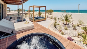A hot tub with a wooden deck, a covered seating area, and a view of the beach. - Paralos Kosta Alímia (Hersonissos)