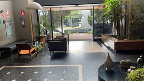 Een moderne lobby met zitplaatsen, een receptiebalie en uitzicht op buiten.