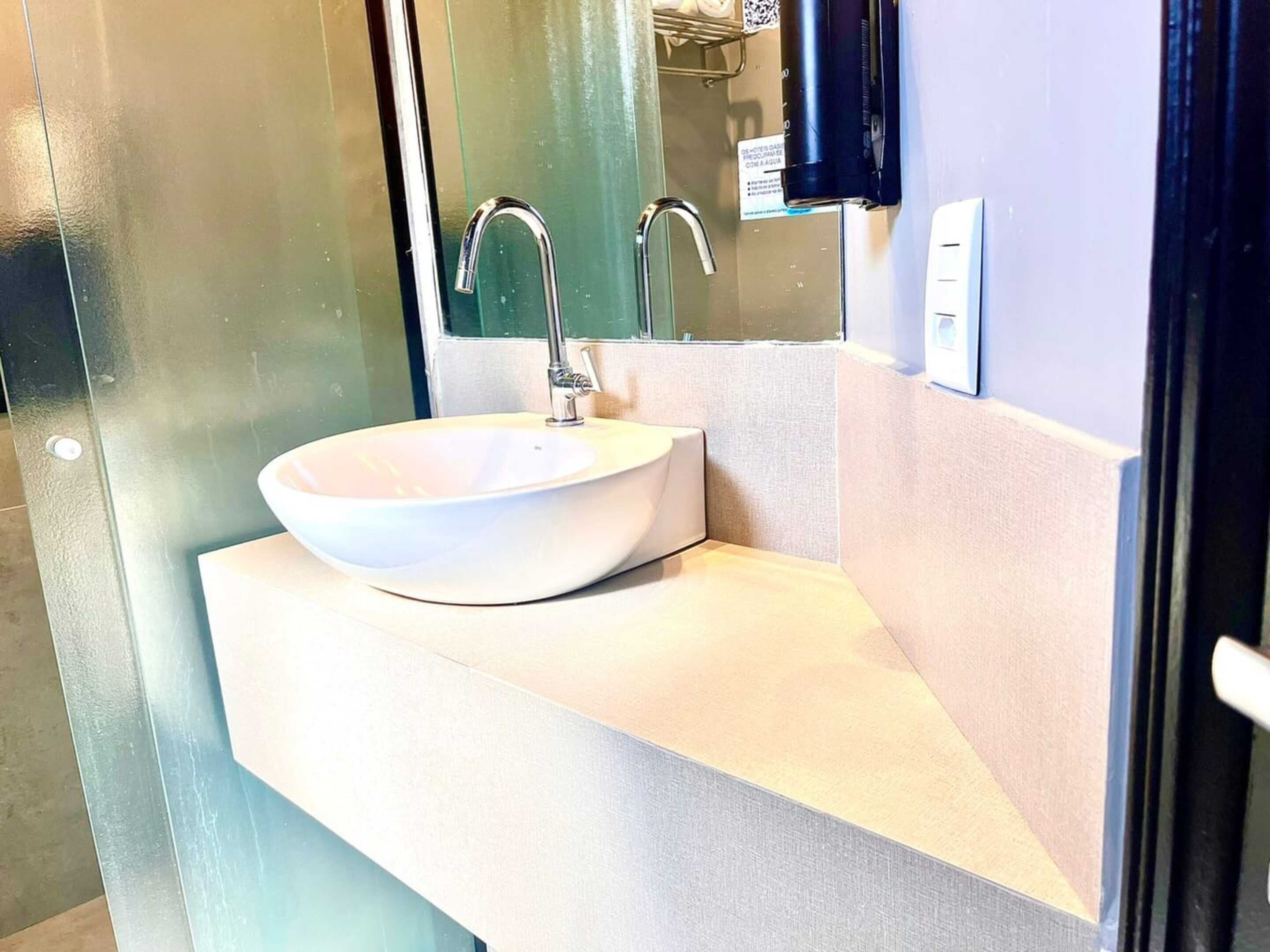 Een moderne badkamer met een witte wastafel, een spiegel en een handdoekhouder.