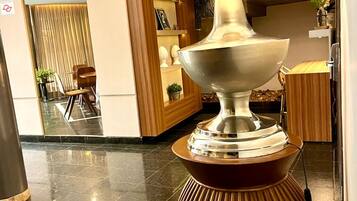 A modern lobby with a large, metallic, sculptural light fixture on a wooden pedestal.