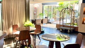 Een moderne hotel lobby met een ronde tafel, stoelen en een decoratieve metalen schommelstoel.