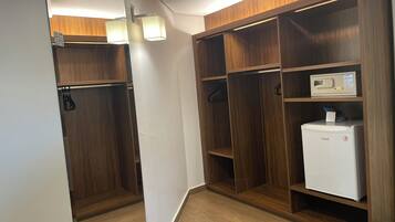 A walk-in closet with wooden shelving, a white refrigerator, and a hanging garment rack.