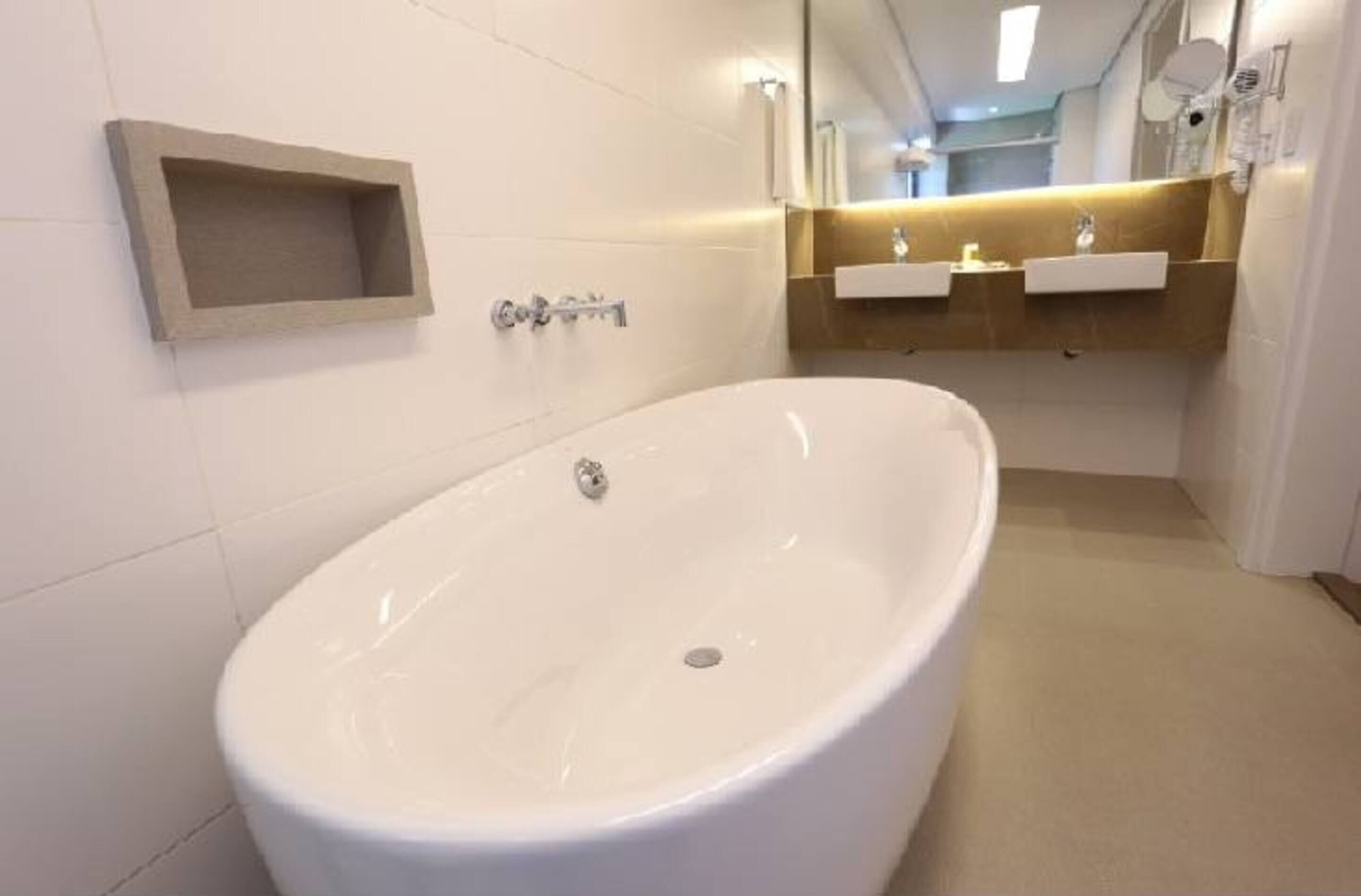 A modern bathroom with a freestanding bathtub, a wall-mounted sink, and a vanity with a mirror.