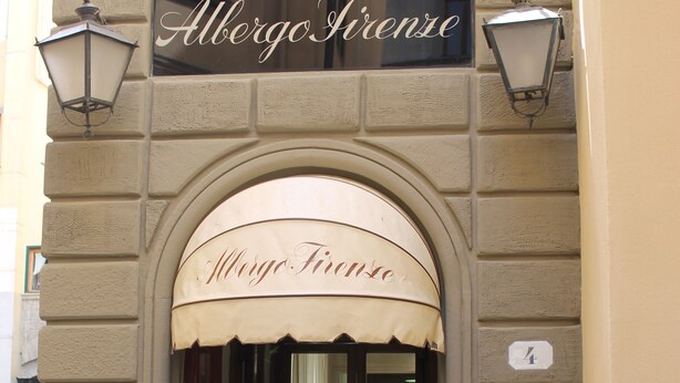 A building entrance with a sign reading "Albergo Firenze" and a small potted plant at the bottom. - Albergo Firenze (Florence)