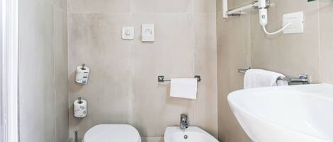 A modern bathroom with a toilet, bidet, and a large bathtub.
