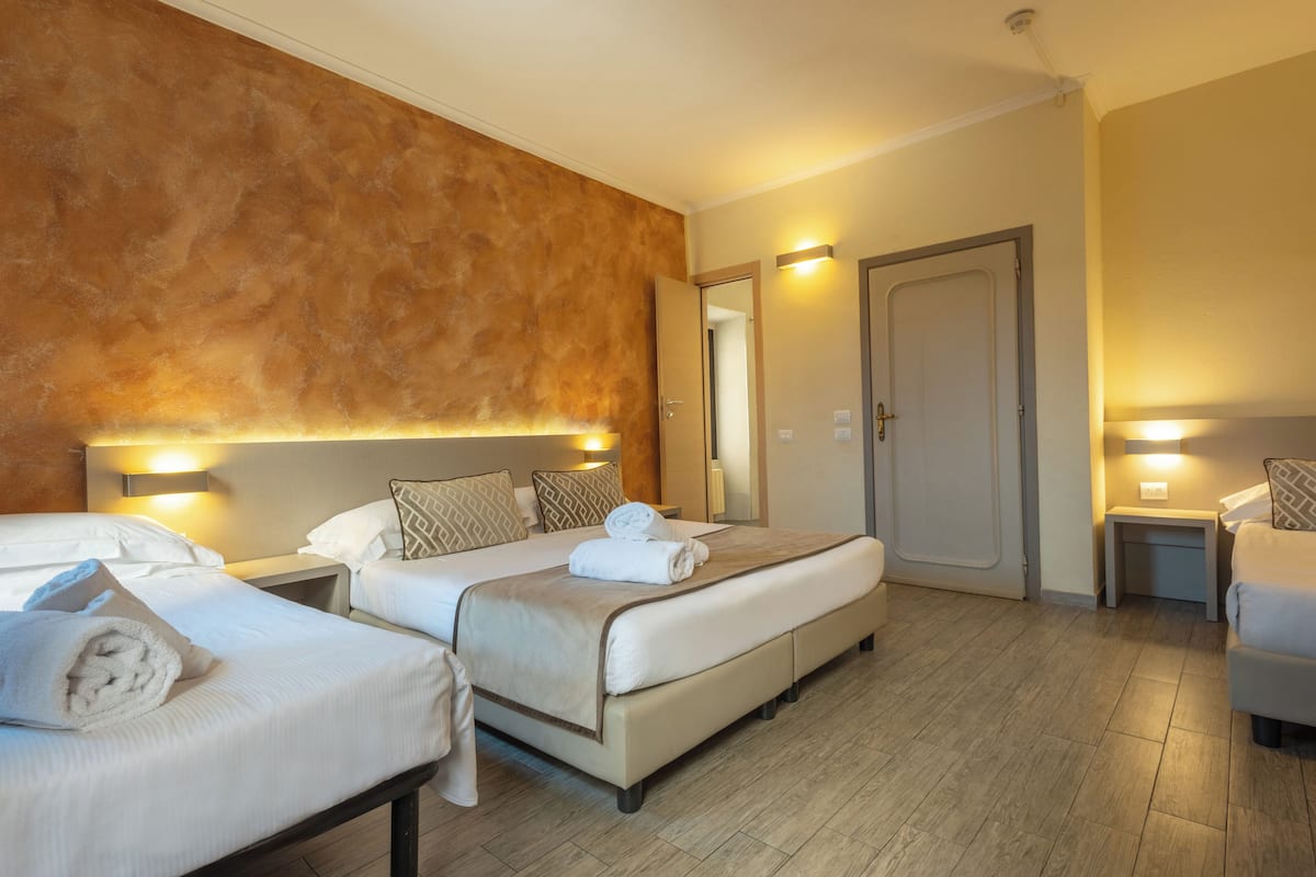 Une chambre d’hôtel avec deux lits, un grand miroir et une porte.