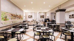 A restaurant with multiple tables and chairs, a counter with a menu, and wall art. - Albergo Firenze (Florence)