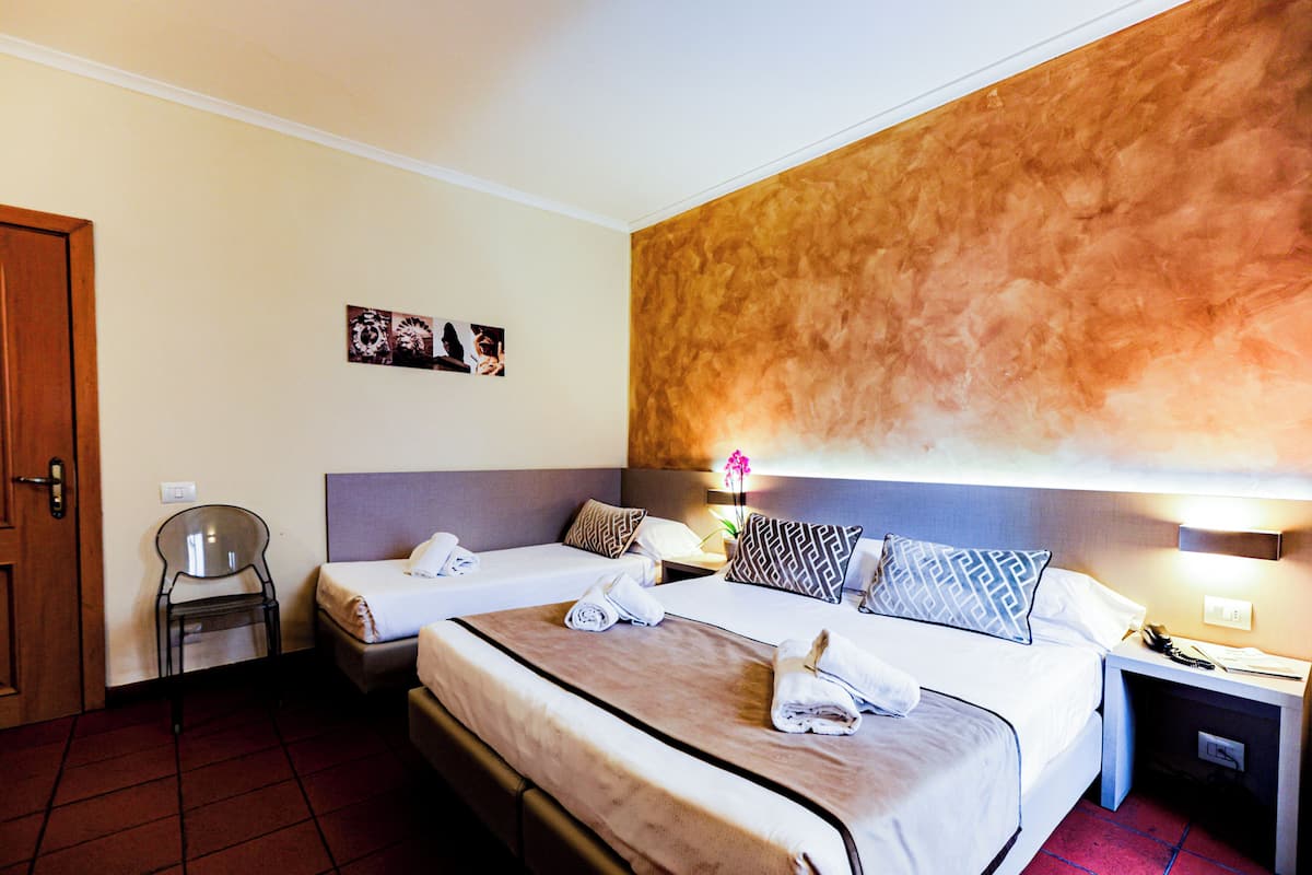 Une chambre d’hôtel avec deux lits, une chaise, une table de chevet et un mur au décor texturé.