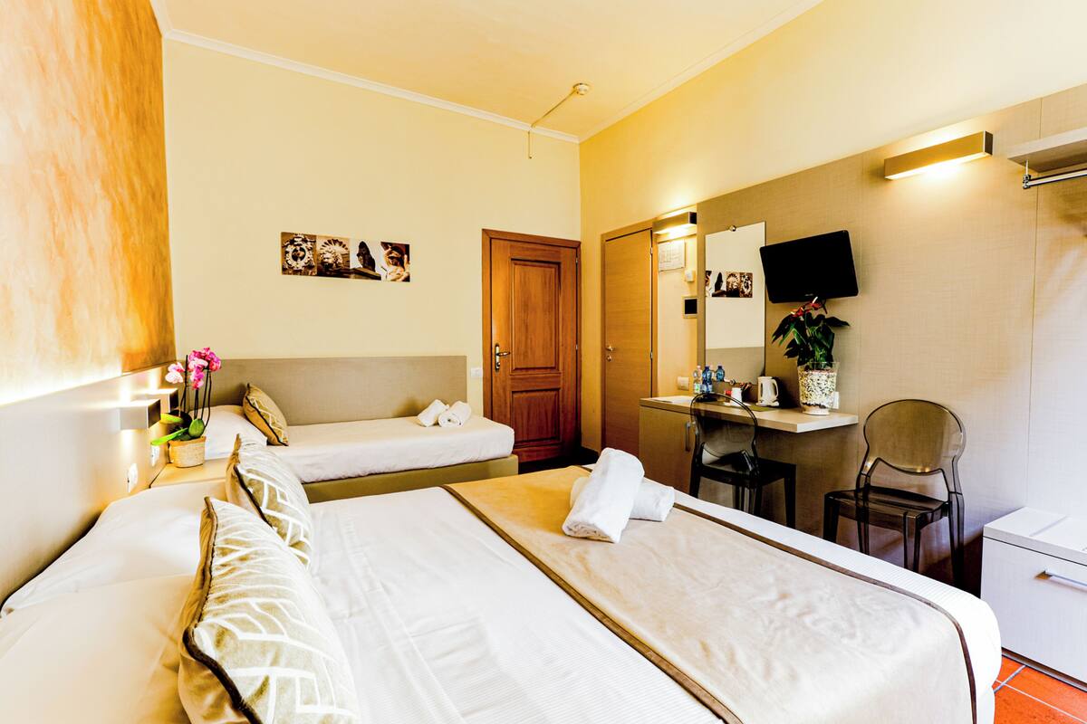 Une chambre d’hôtel avec deux lits, un bureau, une chaise, une télévision et une salle de bain.