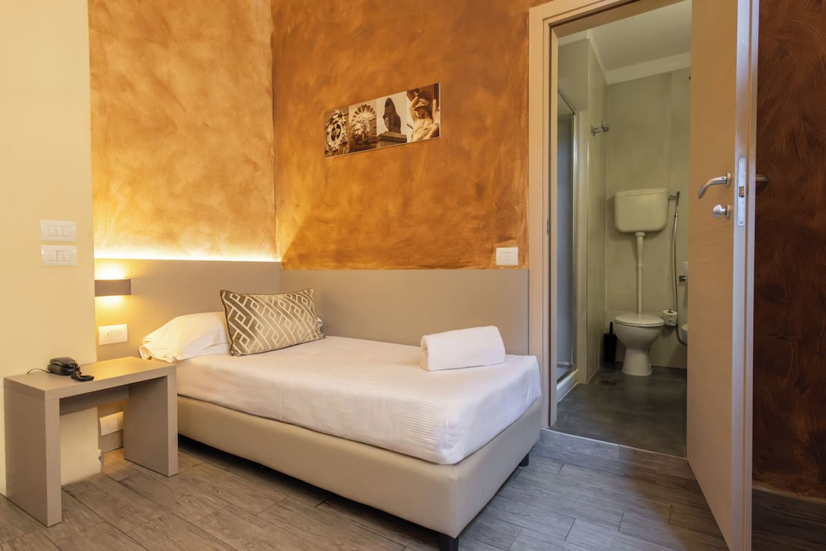 Une chambre à coucher avec un lit, une table de chevet et un tableau accroché au mur.