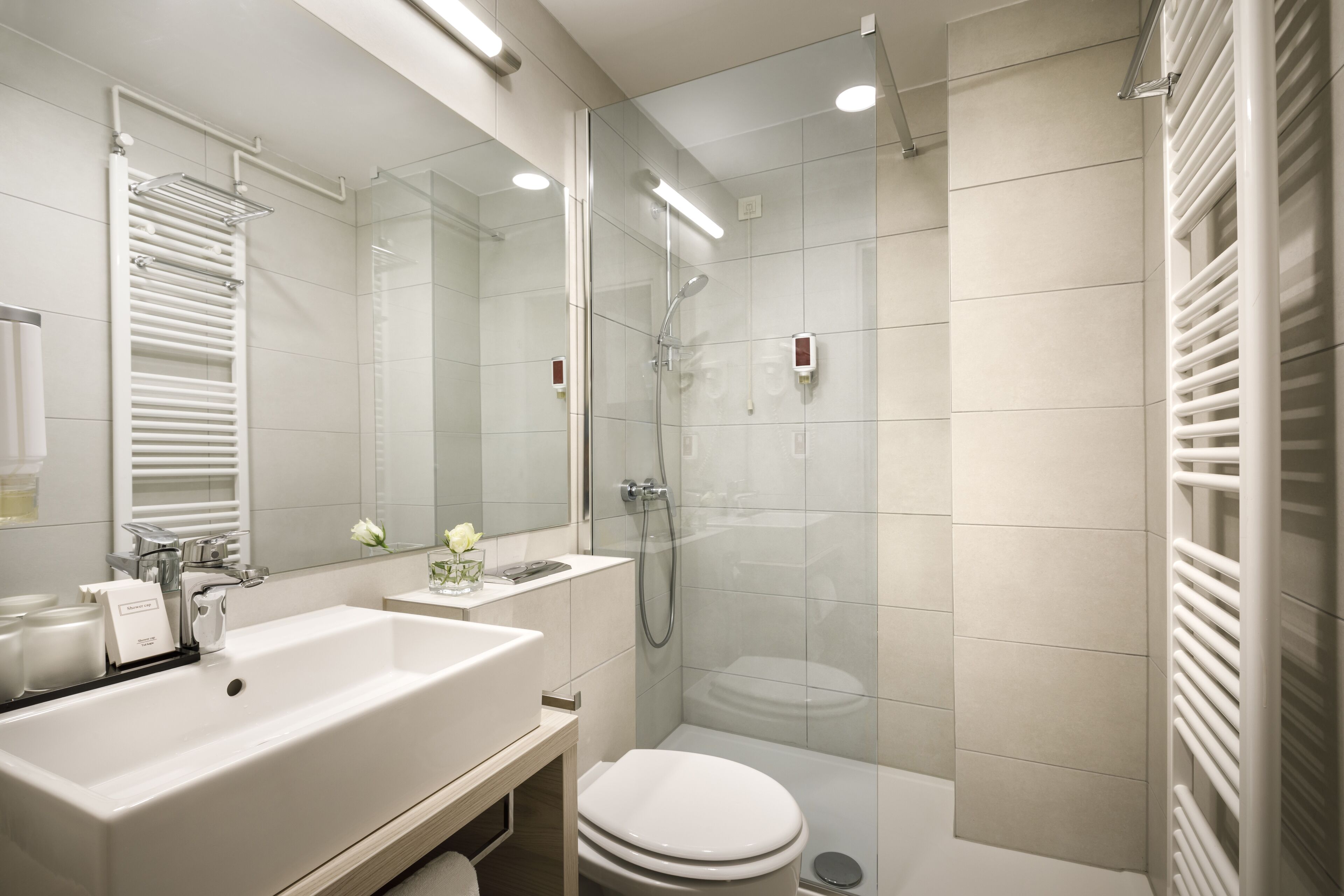 Un bagno moderno con un lavandino ampio, uno specchio e una cabina doccia in vetro.