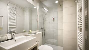 Un bagno moderno con un lavandino ampio, uno specchio e una cabina doccia in vetro.