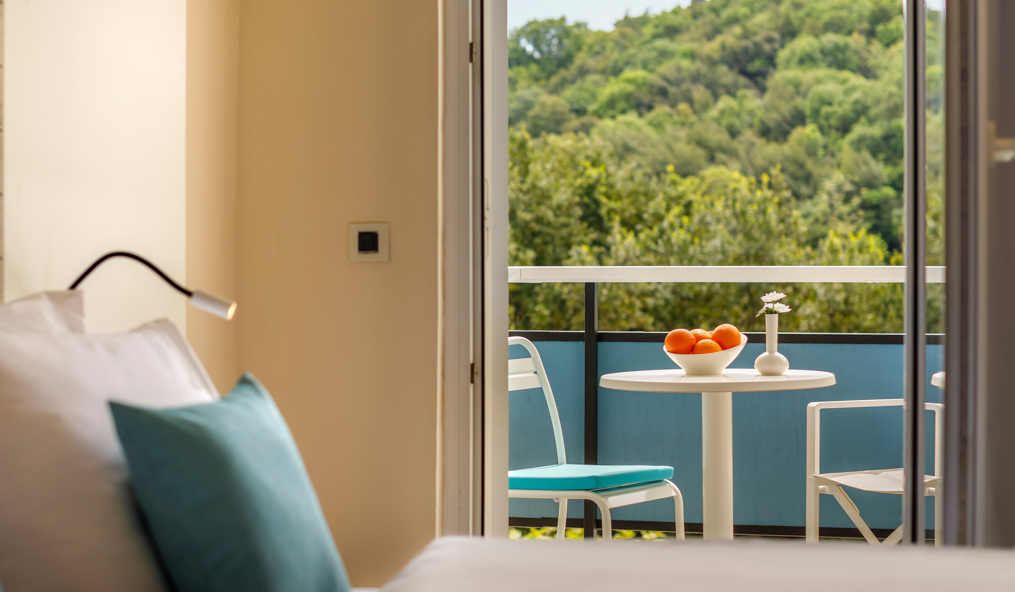 A balcony with a table, chairs, and a bowl of oranges.