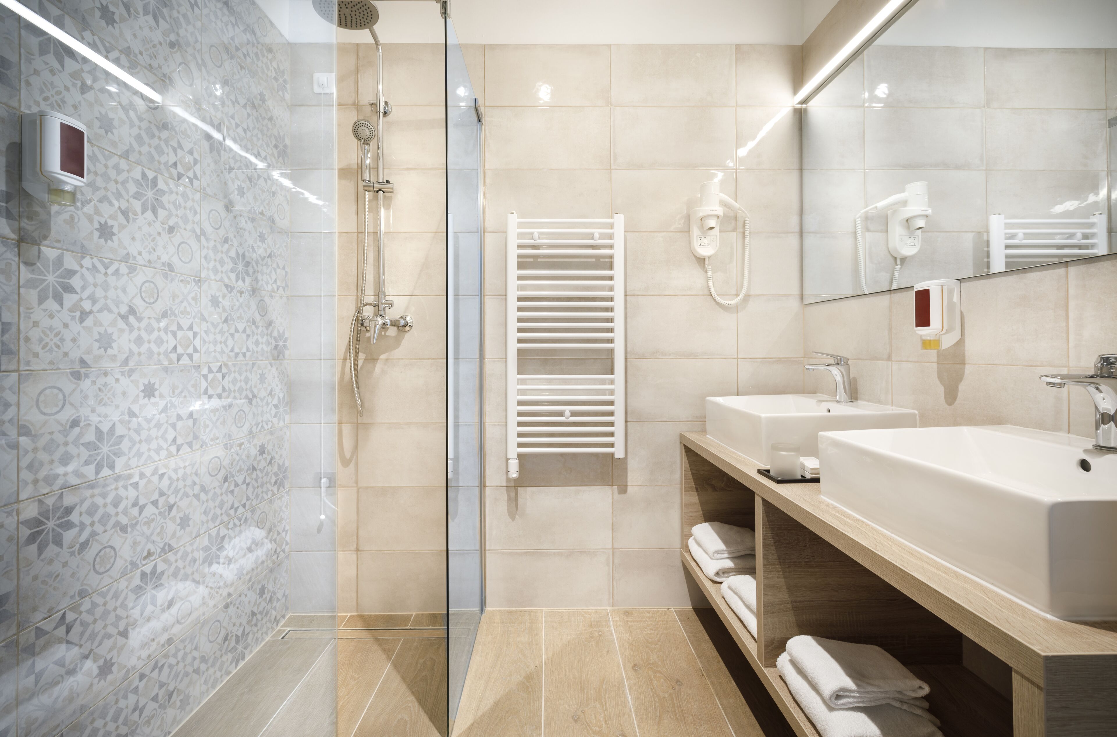 A modern bathroom with a glass-enclosed shower, two sinks, a towel rack, and a mirror.