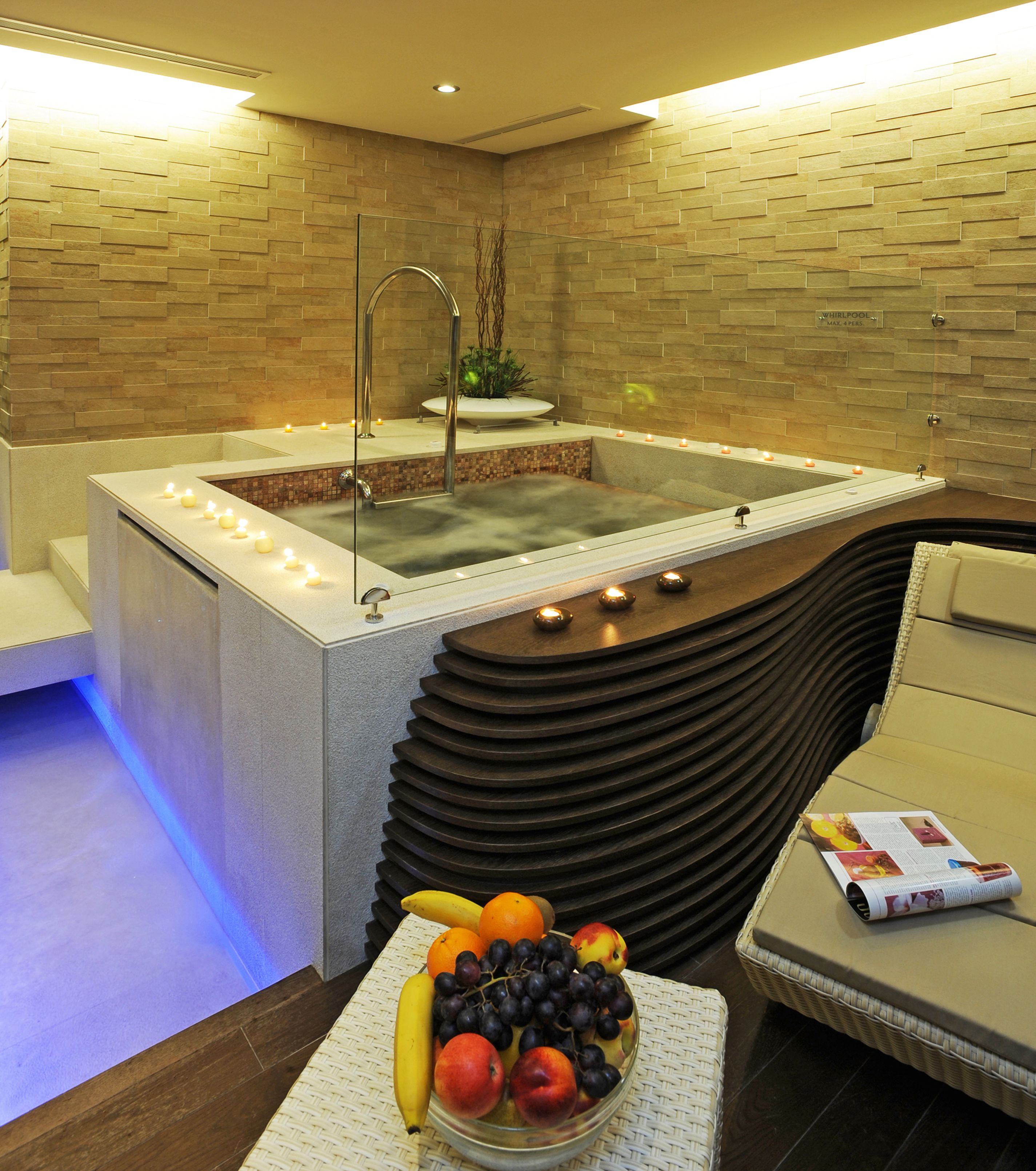 Un espace bien-être comprenant un jacuzzi, un coin salon et un panier de fruits.