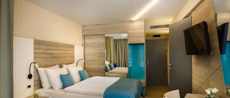 A modern hotel room with a large bed, bedside tables, a flat-screen TV, and a mirror.