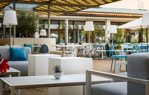 An outdoor seating area with white furniture, including sofas and tables, and umbrellas.