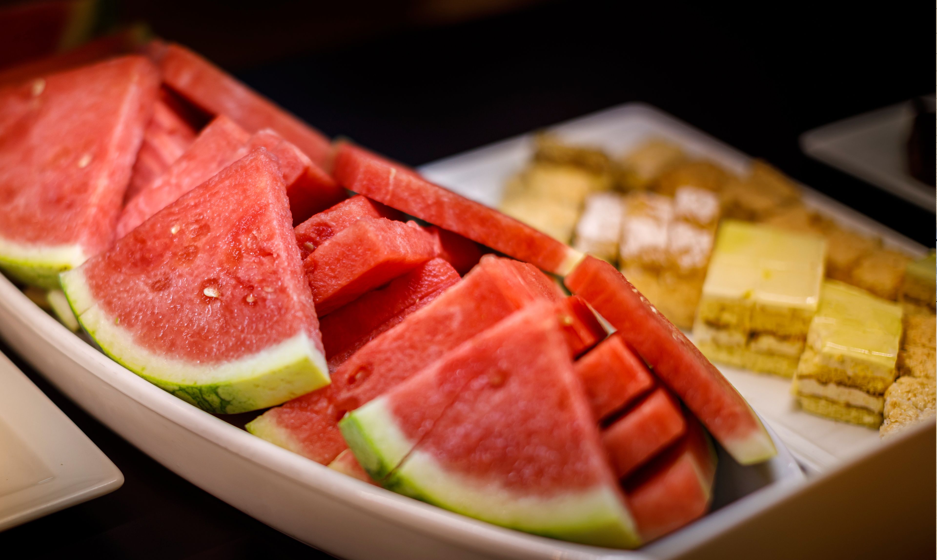 A tray of sliced watermelon and various pastries.