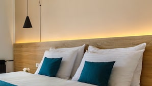 A modern bedroom with a wooden headboard, a bed with white and teal bedding, and a pendant light.