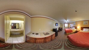 A hotel room with a kitchenette, two beds, a bathroom, and a hallway leading to another room. - Deluxe Inn & Suites (Raymondville)