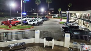 A parking lot with multiple cars and a hotel building in the background. - Deluxe Inn & Suites (Raymondville)