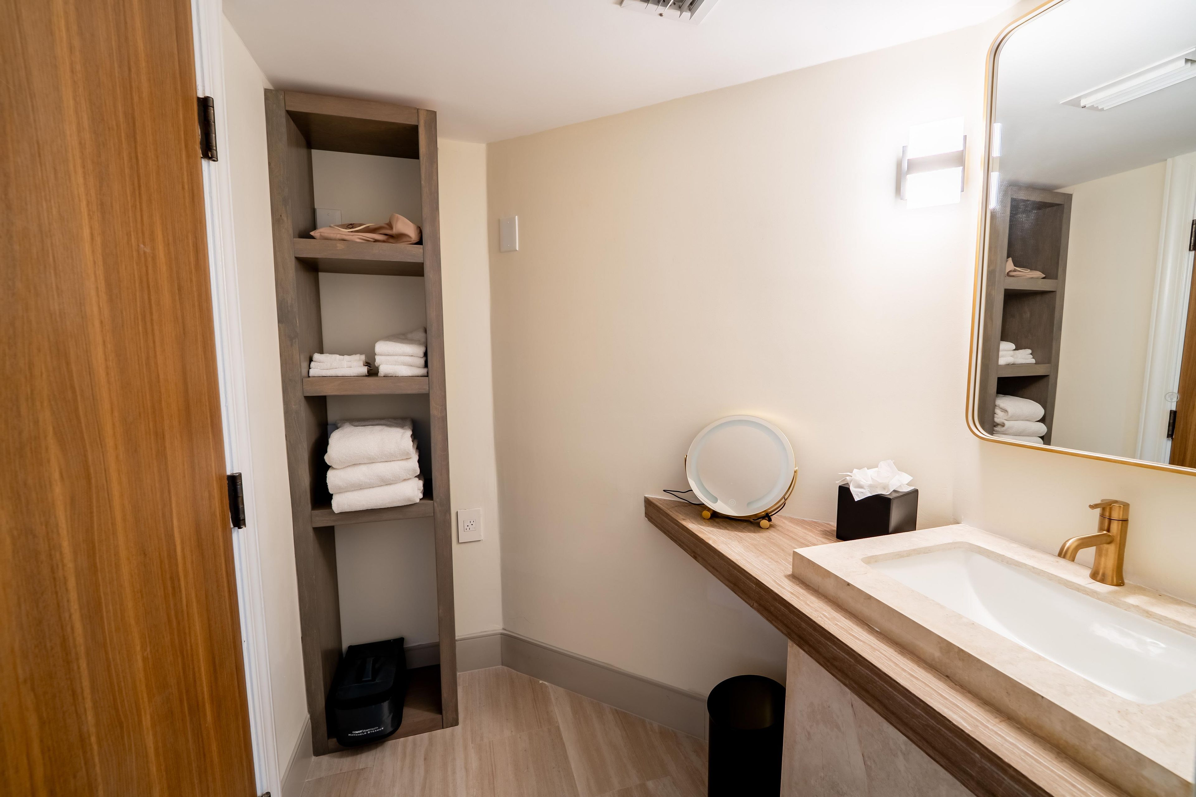 A bathroom with a wooden vanity, a mirror, a sink, and a towel rack.