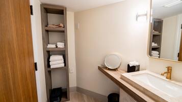 Une salle de bain avec un meuble-lavabo en bois, un miroir, un lavabo et un porte-serviettes.