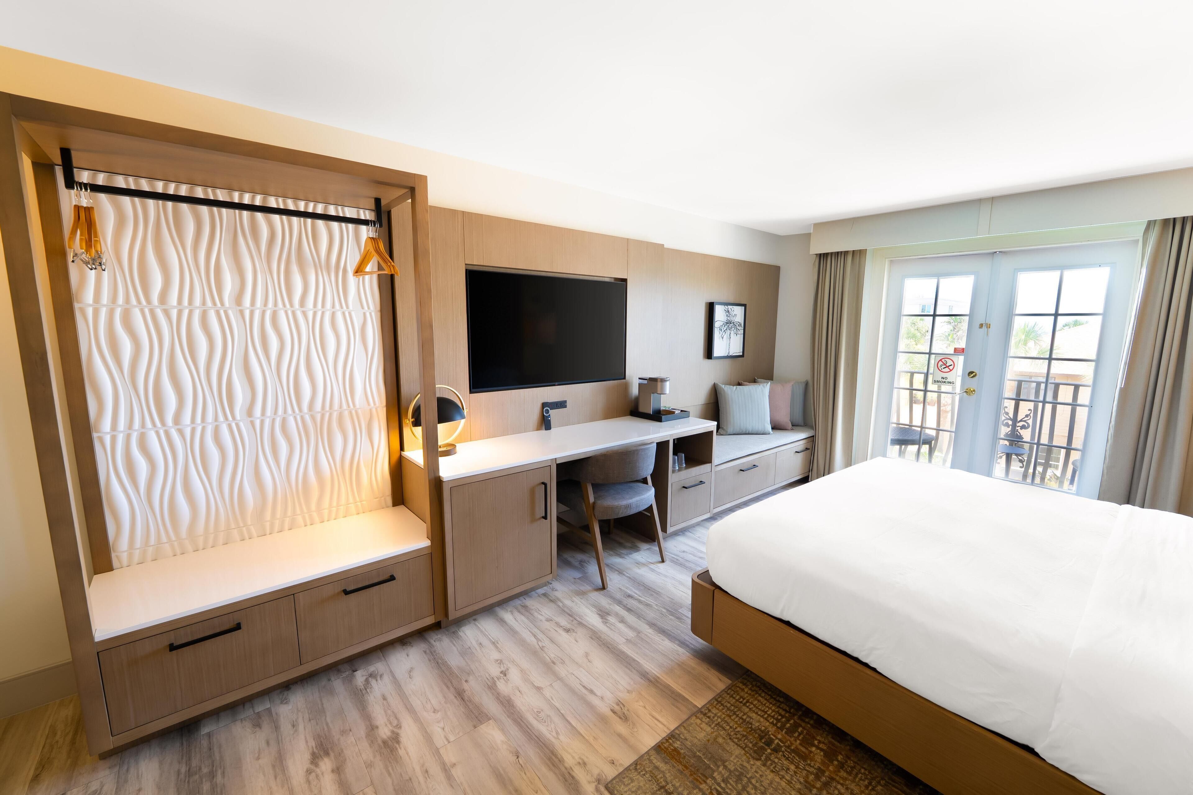 A modern hotel room with a bed, desk, and seating area.