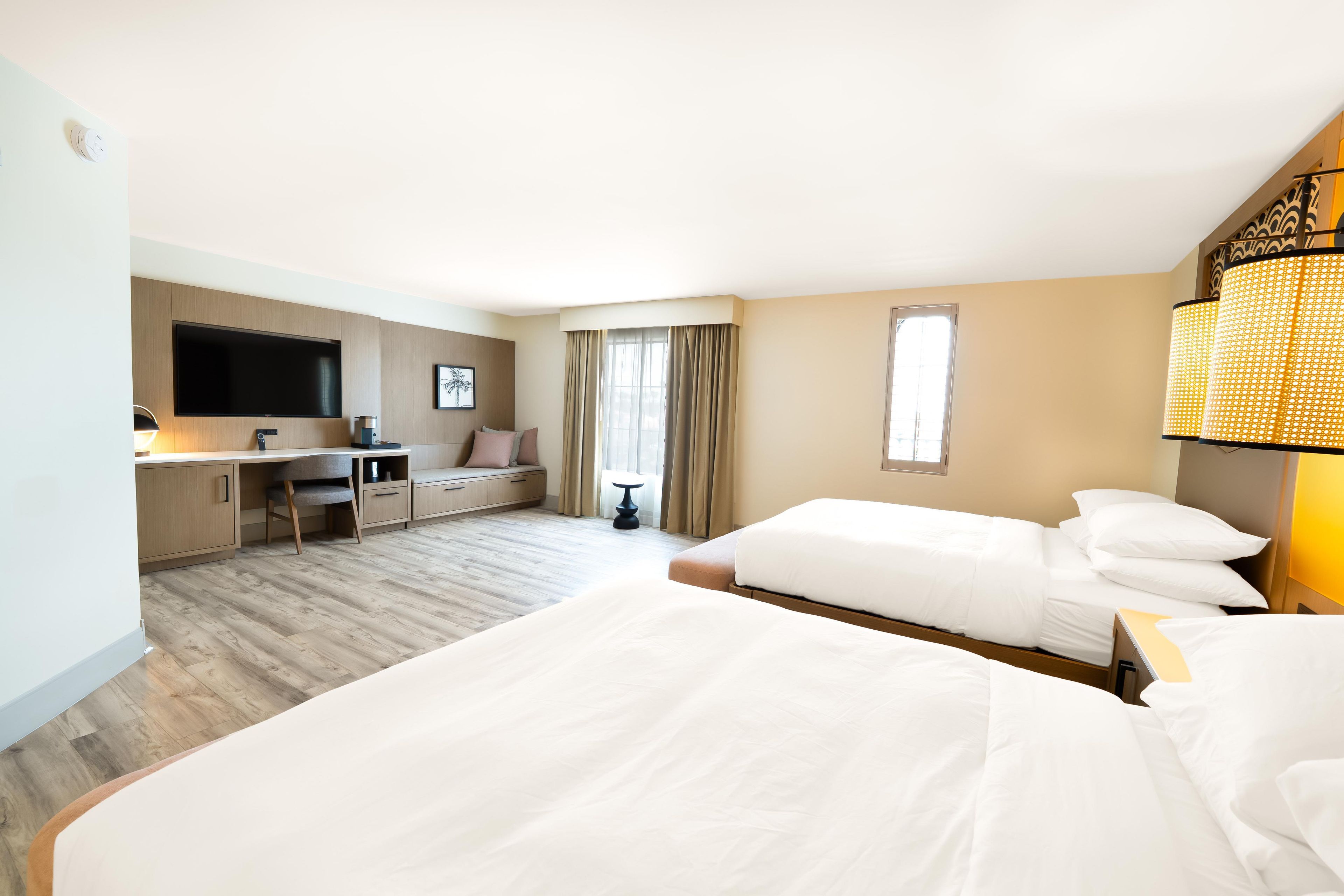 A hotel room with a bed, desk, chair, and a TV.