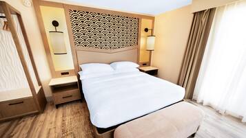 Ett hotellrum med en stor säng, sängbord, en garderob och en dekorativ sänggavel.