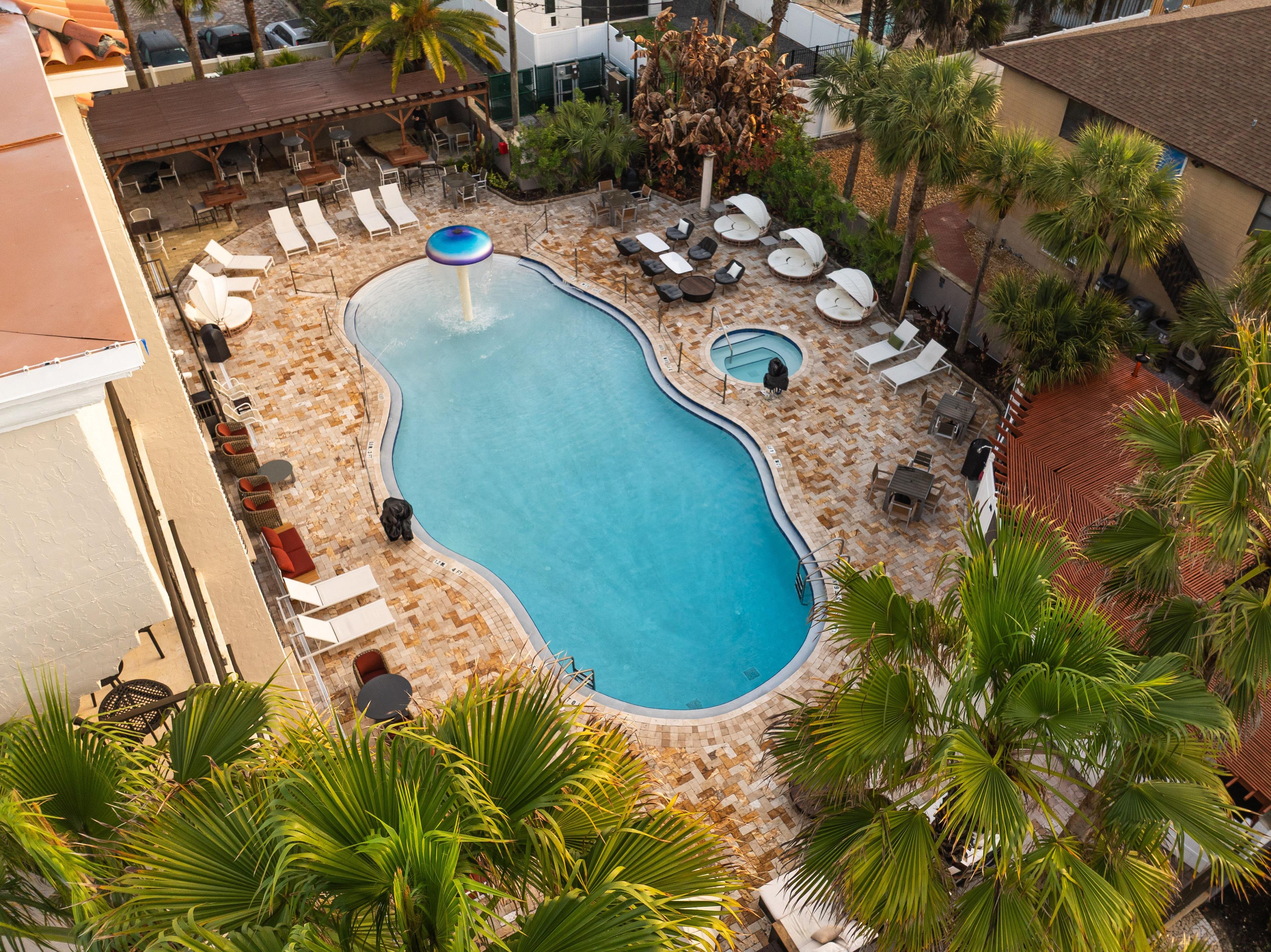 A swimming pool with lounge chairs and palm trees.
