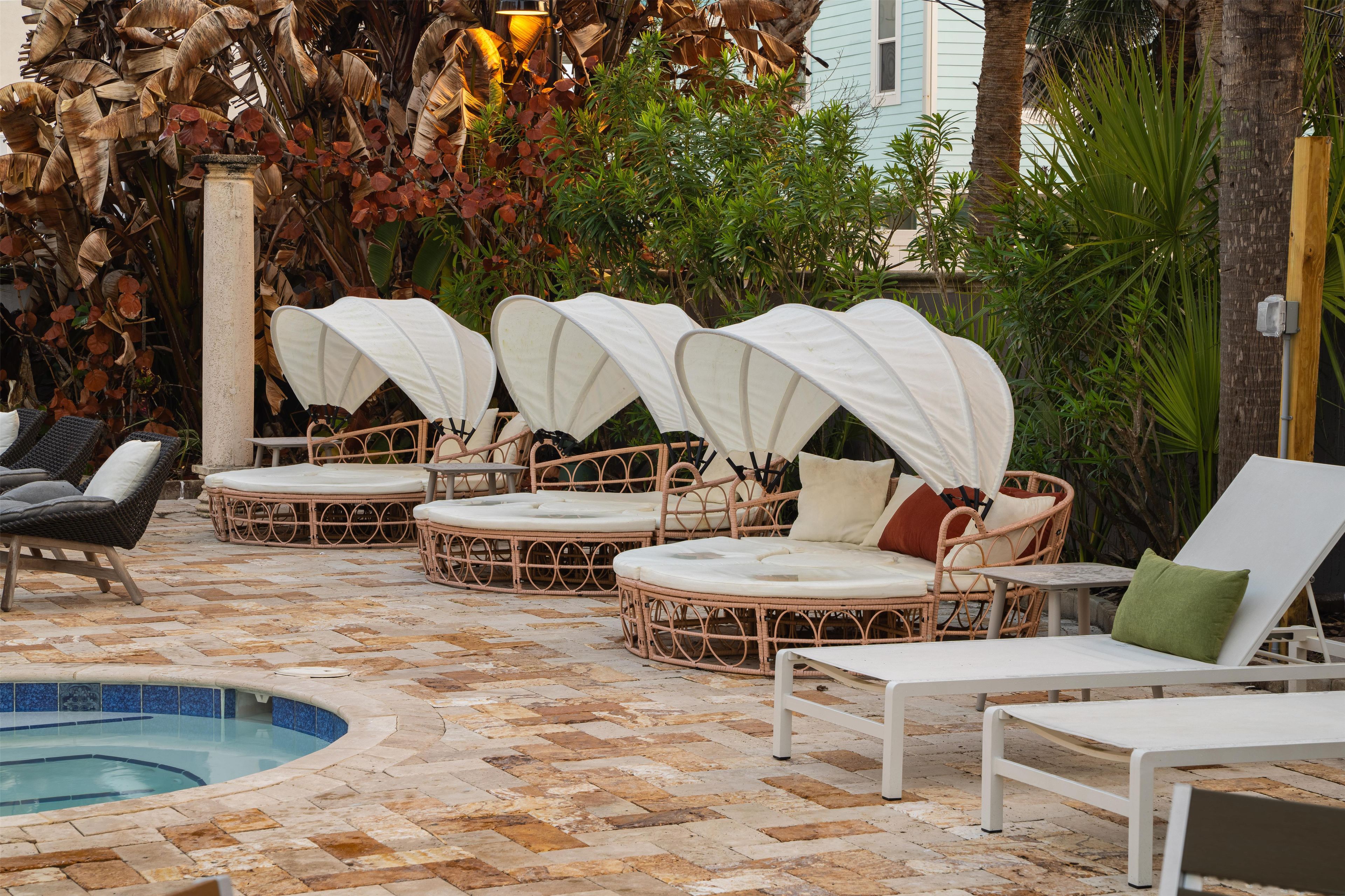 A poolside area with wicker lounge chairs, a small pool, and surrounding foliage.