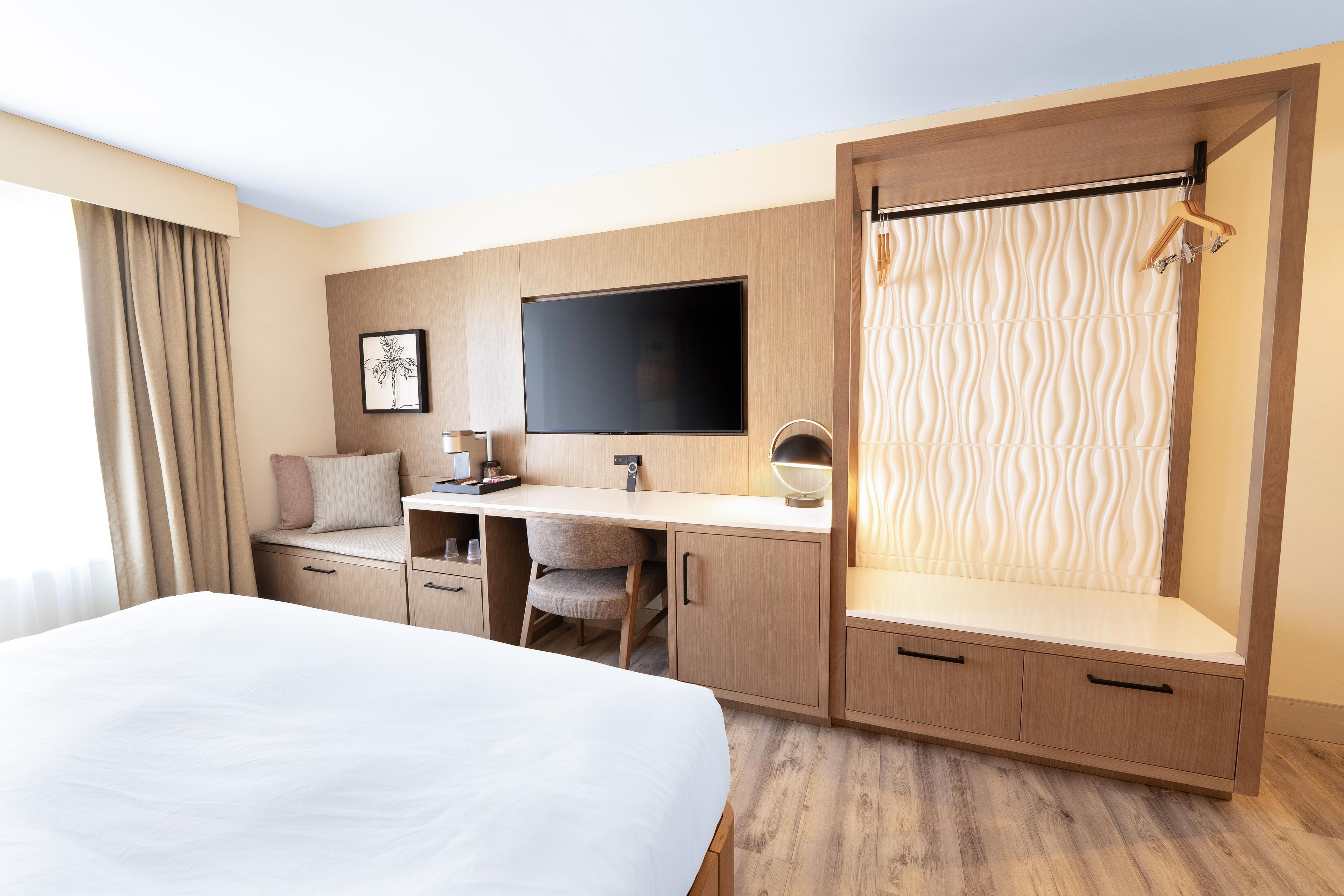 Een hotelkamer met een bed, een bureau, een televisie en een douche.