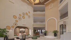 A spacious lobby with a modern design, featuring a fireplace, seating areas, and decorative wall art. - Castillo Real St. Augustine Beach,Tapestry Collection Hilton (St. Augustine)