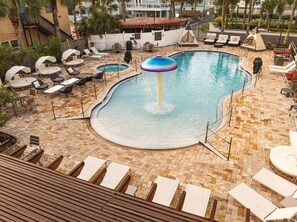 A pool area with lounge chairs, a hot tub, and a small waterfall feature. - Castillo Real St. Augustine Beach,Tapestry Collection Hilton (St. Augustine)