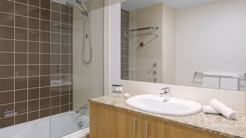 A modern bathroom with a bathtub, a shower, a sink, and a vanity.